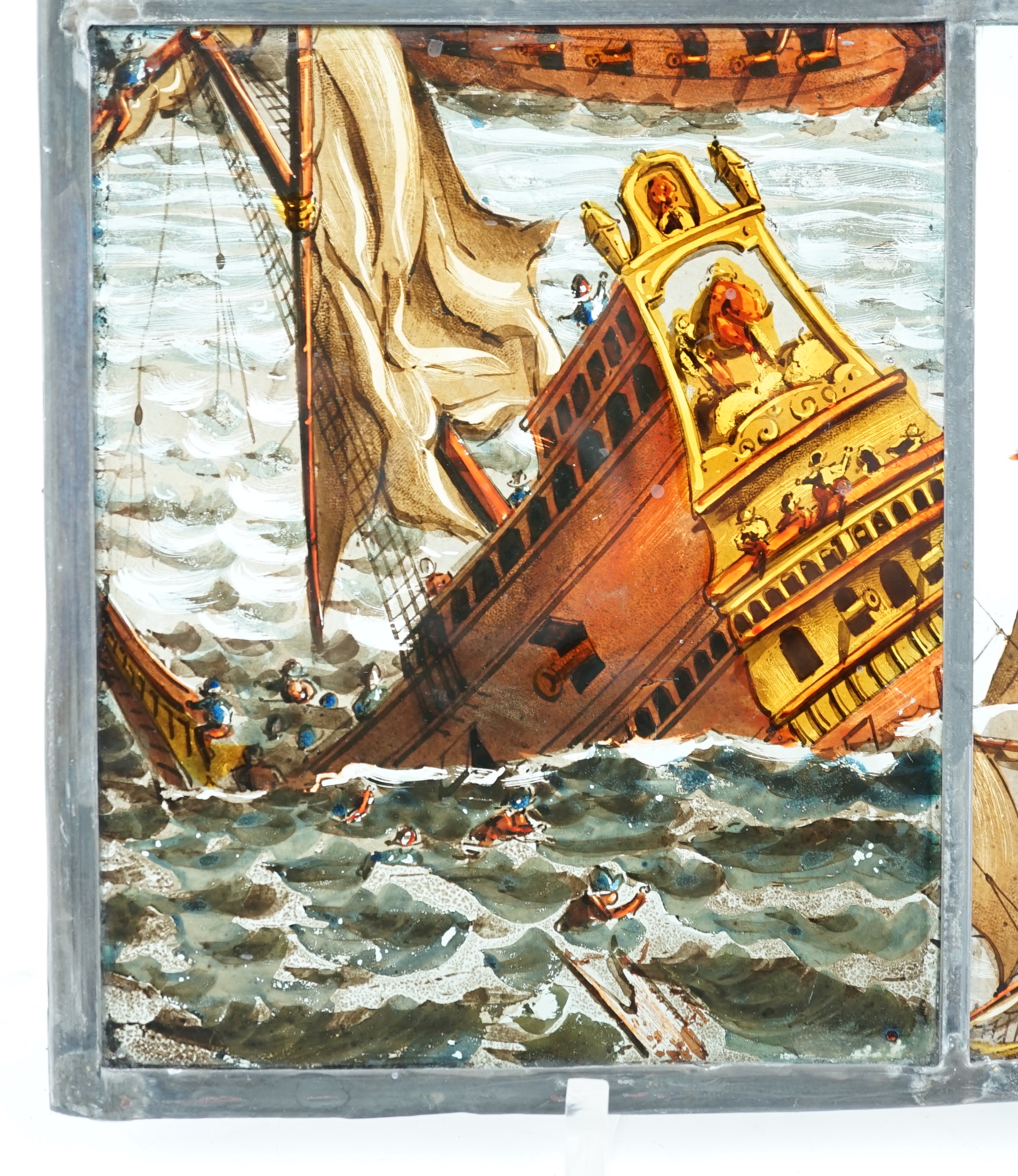 A 18th century Dutch stained glass panel made from four sections depicting a shipwreck and the sails of a fighting galleon, overall 28 x 23cm